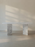 Sienae Dining Table in Carrara Bianco marble with oval-edged tabletop and sculptural V-shaped base, shown from the front