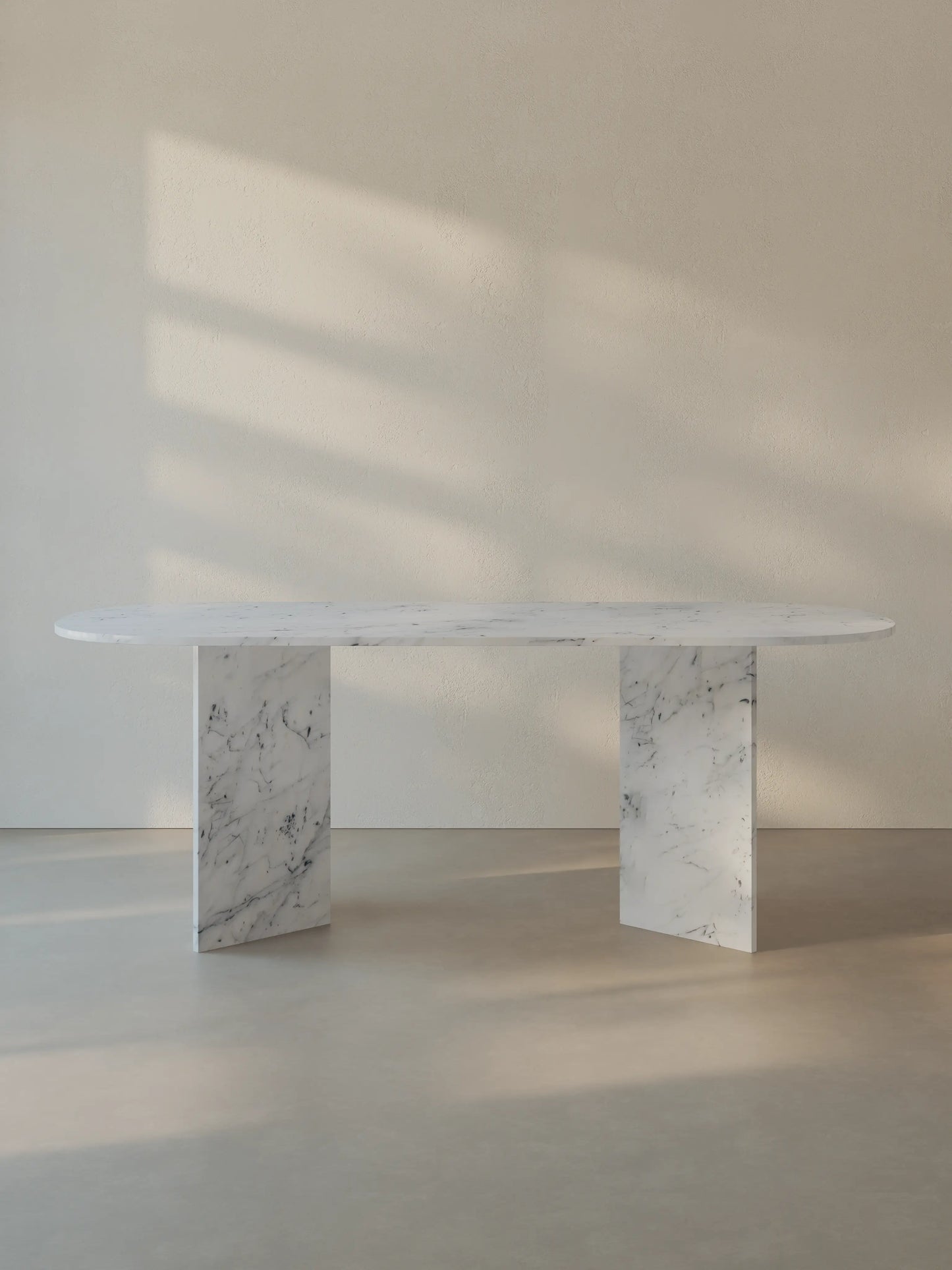 Sienae Dining Table in Carrara Bianco marble with oval-edged tabletop and sculptural V-shaped base, shown from the front