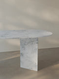 Side view of the Sienae Dining Table in Carrara Bianco marble showing the sculptural V-shaped base