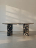 Sienae Dining Table in Dark Emperador marble with oval-edged tabletop and sculptural V-shaped base, shown from the front