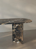 Side view of the Sienae Dining Table in Dark Emperador marble showing the sculptural V-shaped base