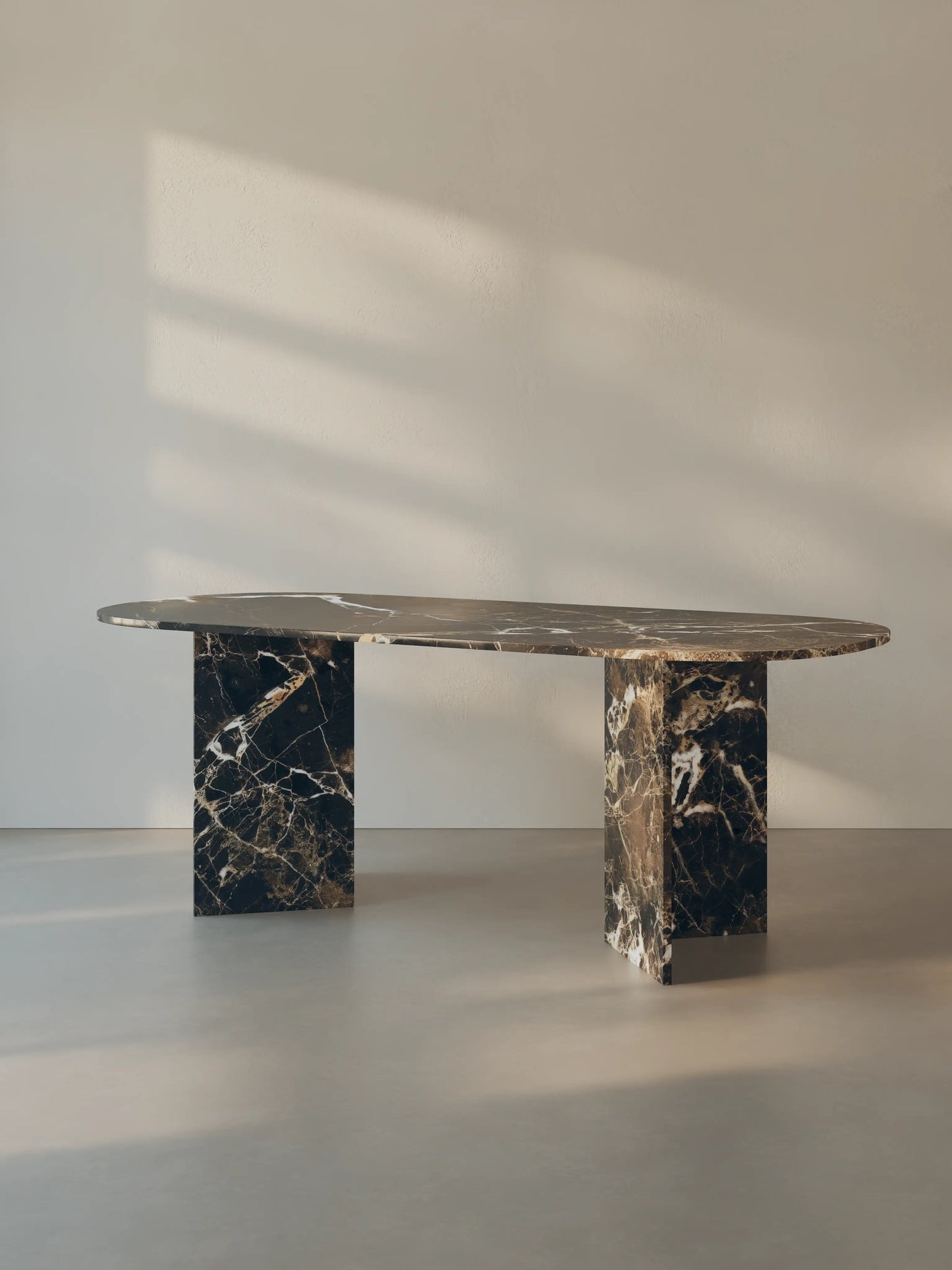 Sienae Dining Table in Dark Emperador marble with oval-edged tabletop, shown from a slight angle highlighting the V-shaped base