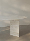Side view of the Sienae Dining Table in Navona Travertine showing the sculptural V-shaped base