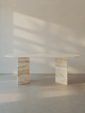 Sienae Dining Table in Roman Travertine with oval-edged tabletop and sculptural V-shaped base, shown from the front.