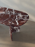 Detail view of the oval-edged tabletop of the Sienae Dining Table in Rosso Levanto marble