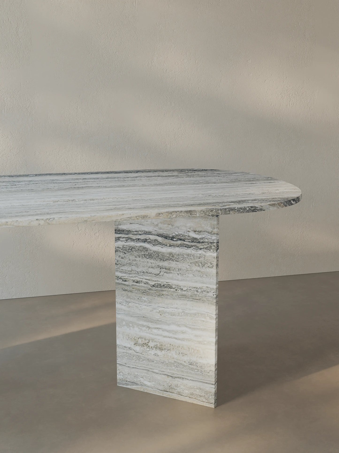 Side view of the Sienae Dining Table in Silver Travertine, emphasizing the V-shaped base and softly rounded tabletop edges.