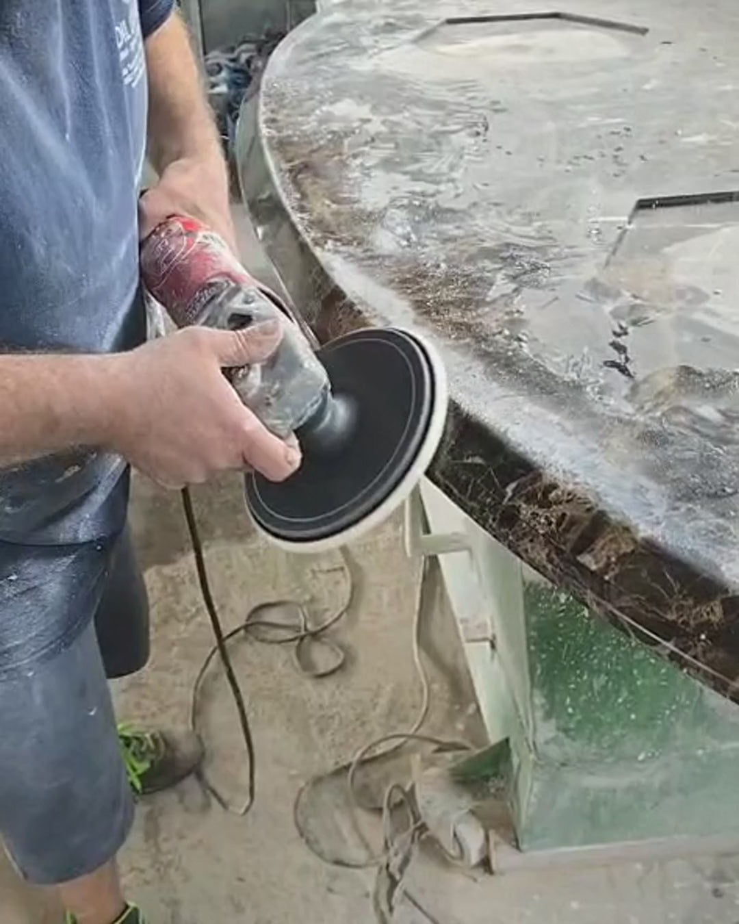 Dark Emperador marble tabletop edge being polished by hand