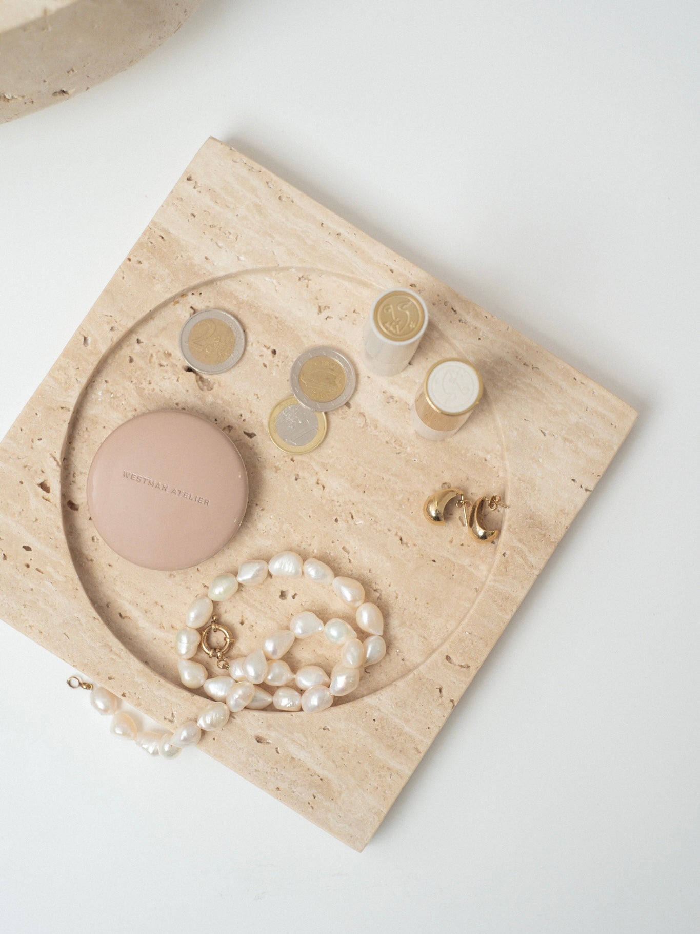 Styled Ra Catchall with various small objects, including Euro coins and makeup, emphasizing its versatile use.